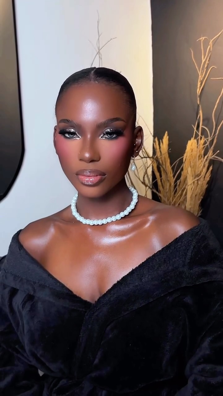 Alima in a black fur coat with a pearl choker and glittering silver eye makeup