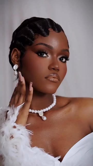 Angela as a bride with finger-wave hair, pearl necklace and feather-trimmed white dress